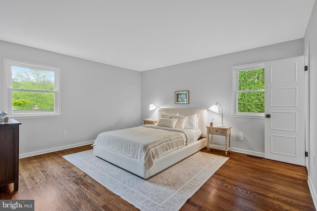 bedroom featuring multiple windows, baseboards, and dark wood-style floors