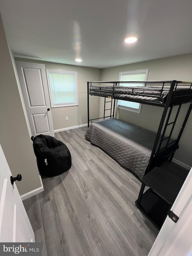 bedroom featuring recessed lighting, baseboards, multiple windows, and wood finished floors