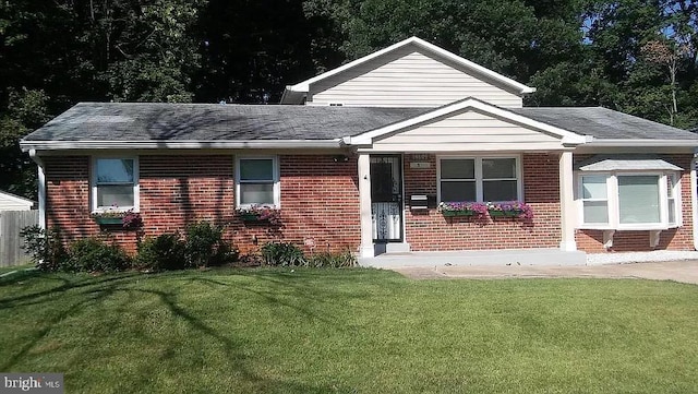 view of front of property with brick siding, a shingled roof, and a front lawn