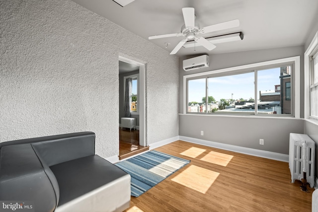 3700 13th St NW, Washington, DC 20010 - living area featuring a wall mounted air conditioner, radiator, a textured wall, wood finished floors, and a ceiling fan