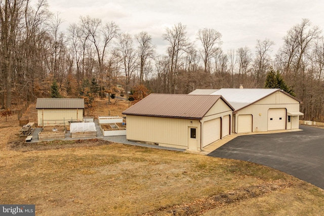 view of home's exterior featuring metal roof, an outdoor structure, and driveway