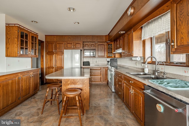 kitchen featuring a sink, brown cabinetry, stainless steel appliances, and under cabinet range hood