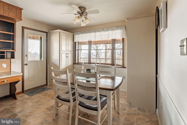 dining space featuring baseboards, stone finish floor, and a ceiling fan