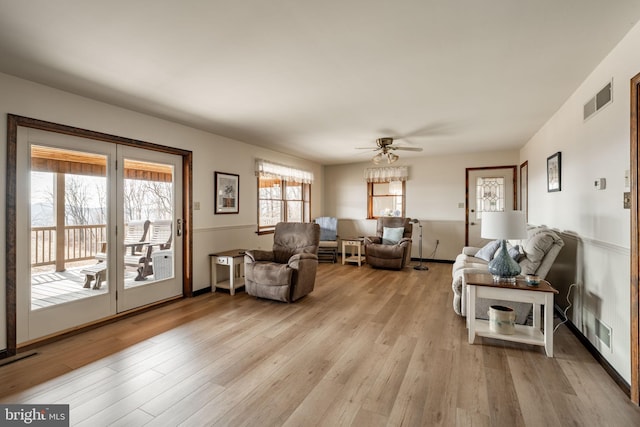 living room featuring ceiling fan, light wood-type flooring, and visible vents