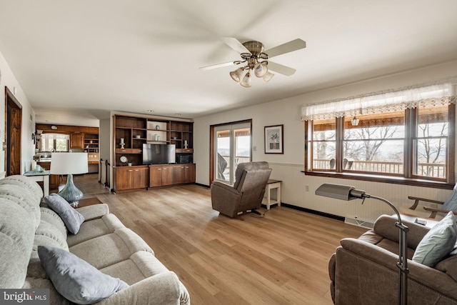 living room with plenty of natural light, baseboards, light wood-style flooring, and a ceiling fan