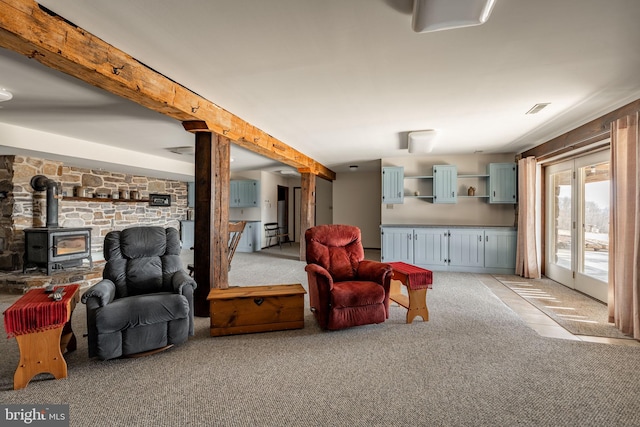 living room featuring a wood stove, light carpet, and beamed ceiling