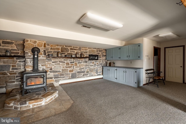 interior space featuring a wood stove, carpet floors, and visible vents
