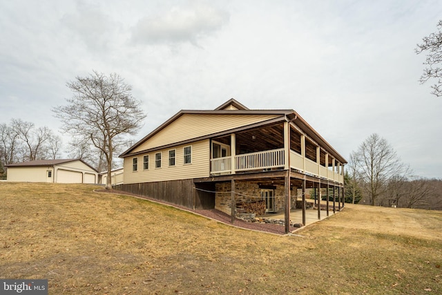 rear view of property with a lawn, a wooden deck, and a detached garage