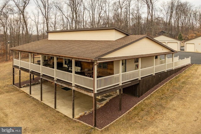 back of house with an outbuilding, a shingled roof, and a detached garage