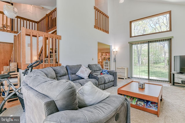 living area with carpet floors, stairs, and high vaulted ceiling