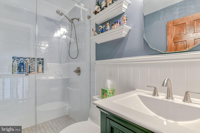 bathroom featuring a sink, wainscoting, a stall shower, and toilet