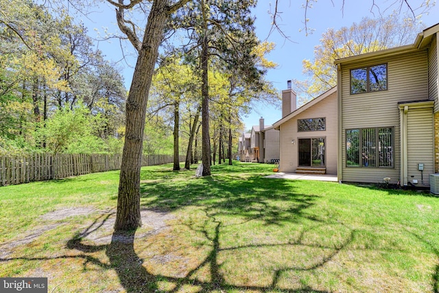 view of yard with fence, central AC unit, and a patio area