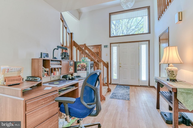 foyer with stairway, a high ceiling, light wood-type flooring, and a wealth of natural light