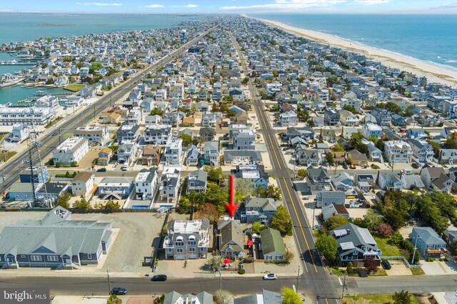 drone / aerial view featuring a water view, a beach view, and a residential view
