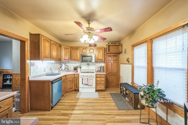 kitchen with light countertops, appliances with stainless steel finishes, a wainscoted wall, and a ceiling fan