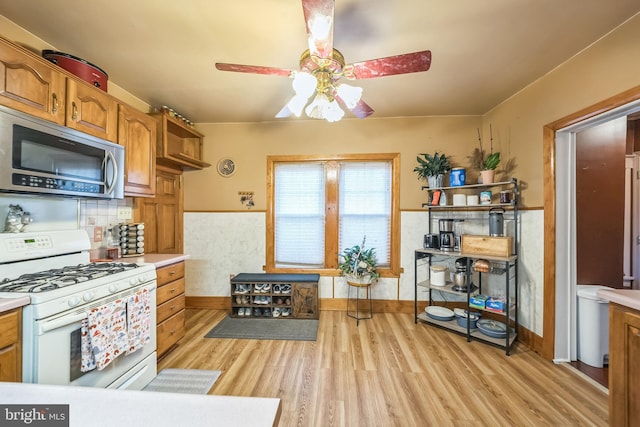 kitchen with gas range gas stove, light wood finished floors, stainless steel microwave, and light countertops