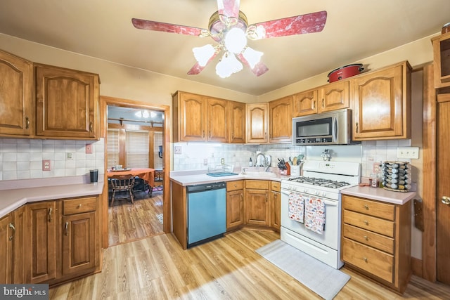 kitchen featuring white gas range, backsplash, stainless steel microwave, dishwashing machine, and light wood-style flooring