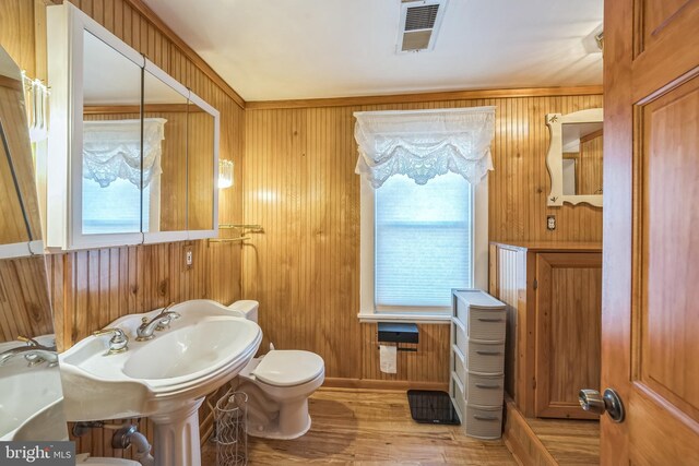 bathroom featuring wooden walls, toilet, wood finished floors, and visible vents