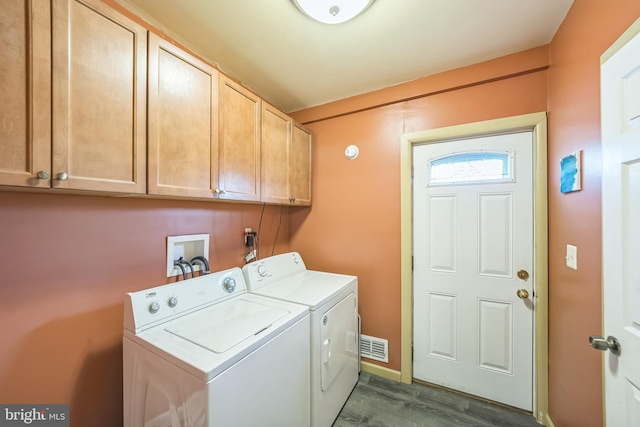 washroom featuring visible vents, dark wood finished floors, cabinet space, and washer and clothes dryer