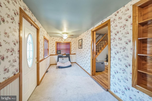 foyer featuring a ceiling fan, wallpapered walls, baseboards, and stairway