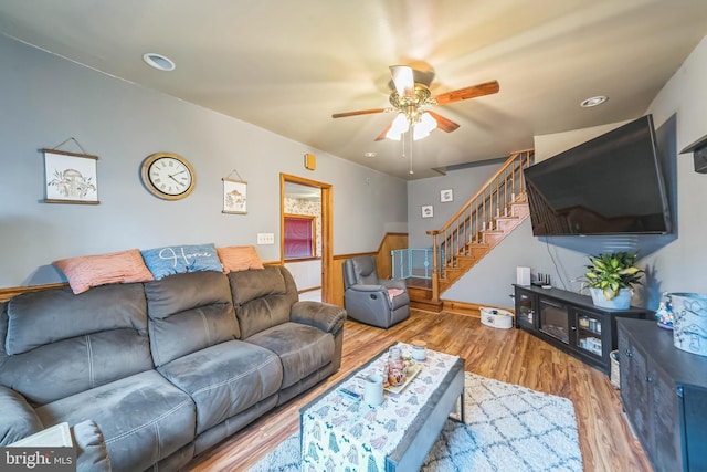 living room with stairs, ceiling fan, baseboards, and wood finished floors