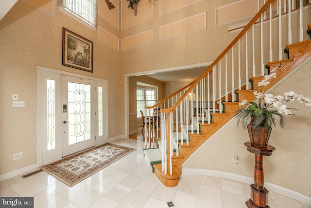 foyer featuring stairway, a towering ceiling, and baseboards