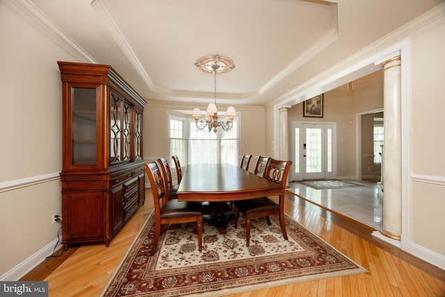 dining space with light wood finished floors, plenty of natural light, ornate columns, and a chandelier