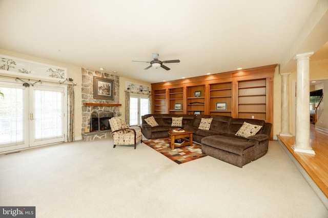 living area featuring a ceiling fan, visible vents, decorative columns, and a stone fireplace