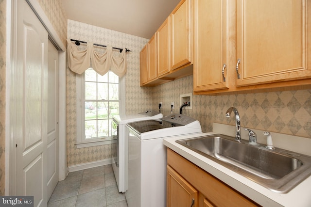 washroom featuring a sink, cabinet space, light tile patterned floors, washing machine and dryer, and wallpapered walls