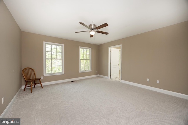 empty room featuring baseboards, light carpet, visible vents, and ceiling fan