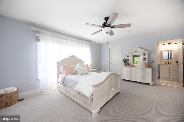 bedroom featuring carpet, a ceiling fan, a sink, baseboards, and ensuite bath