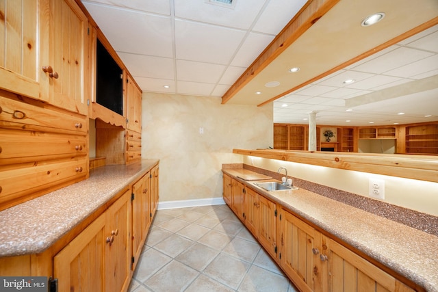 kitchen with a sink, recessed lighting, light tile patterned floors, a drop ceiling, and baseboards