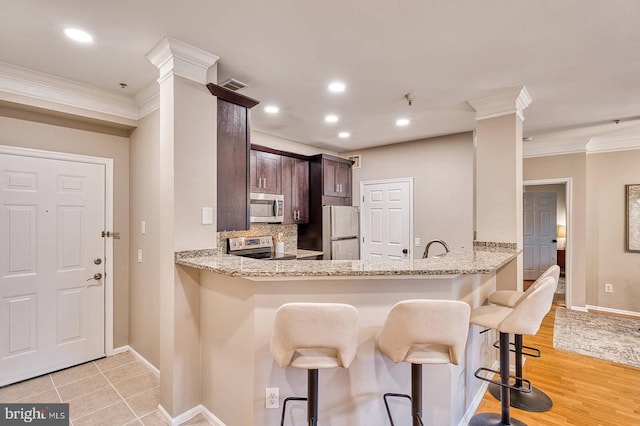 1530 Spring Gate Dr Unit 9208, Mclean, VA 22102 - kitchen with stainless steel appliances, crown molding, ornate columns, baseboards, and dark brown cabinets