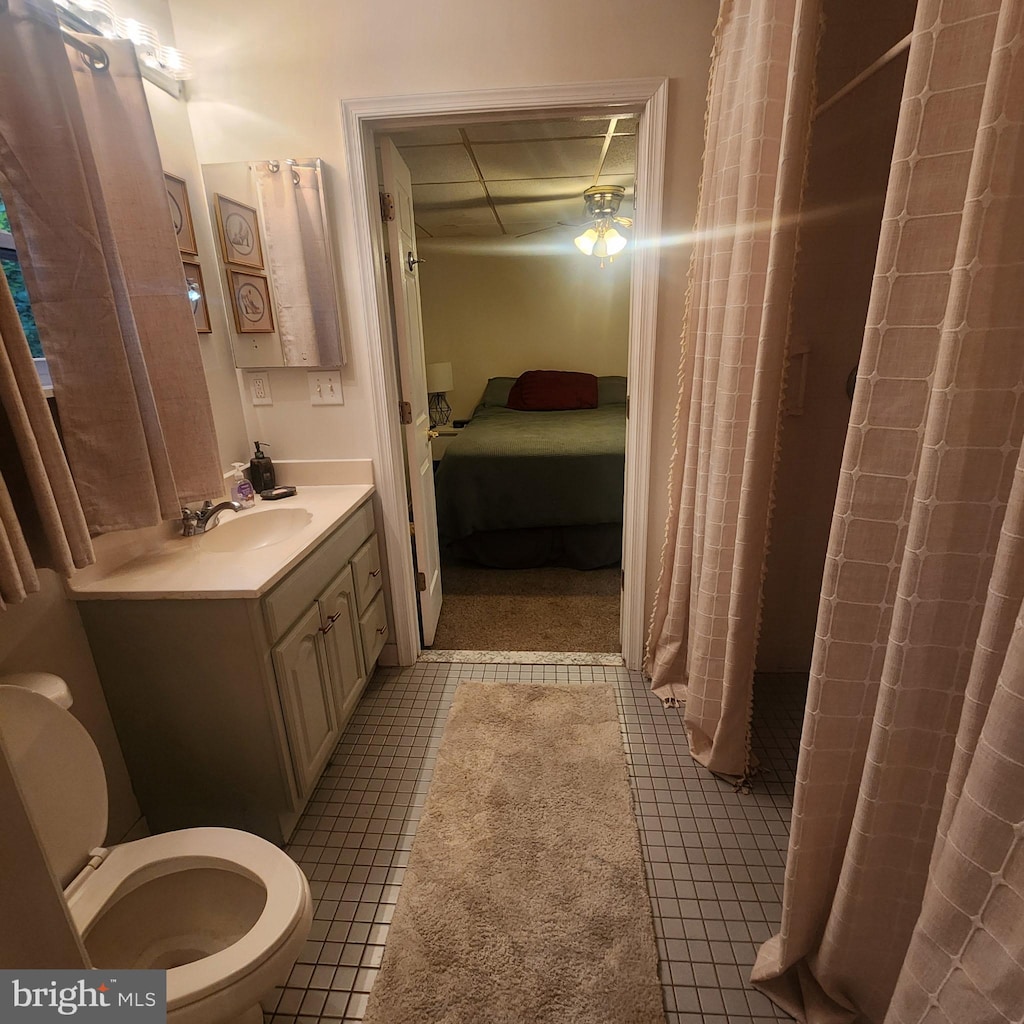 bathroom with a shower with curtain, toilet, tile patterned floors, connected bathroom, and vanity