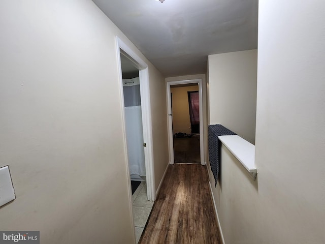 corridor with baseboards and wood finished floors