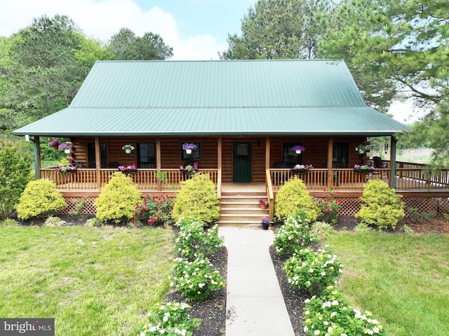 log-style house with log exterior, a front lawn, and a porch