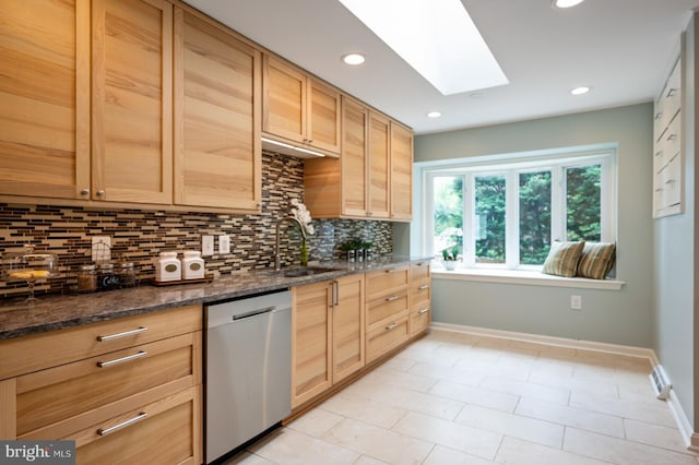 kitchen featuring dishwasher, baseboards, a sink, tasteful backsplash, and a skylight