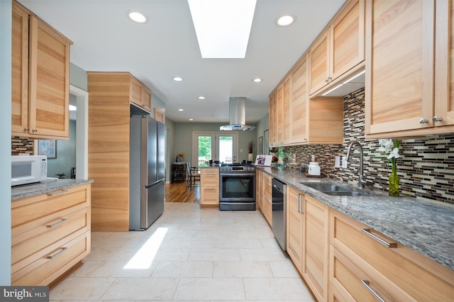 kitchen featuring island exhaust hood, appliances with stainless steel finishes, light brown cabinetry, and a sink