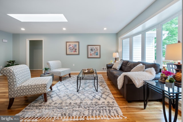 living room featuring a skylight, recessed lighting, visible vents, and wood finished floors