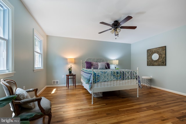 bedroom with baseboards, ceiling fan, visible vents, and wood finished floors
