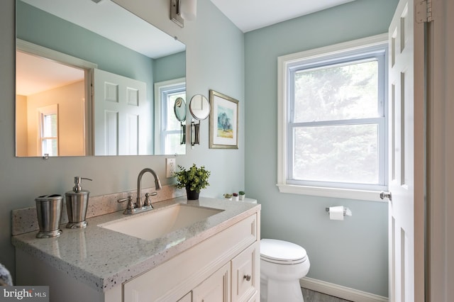 bathroom with toilet, vanity, and plenty of natural light