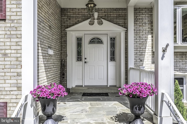 property entrance with a porch and brick siding