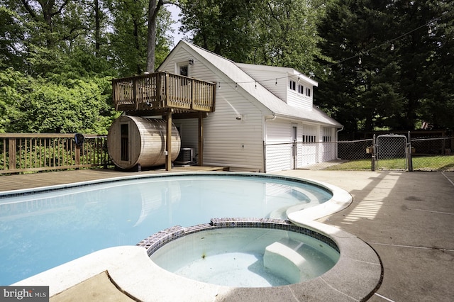 view of pool with fence, a pool with connected hot tub, central air condition unit, a wooden deck, and a gate