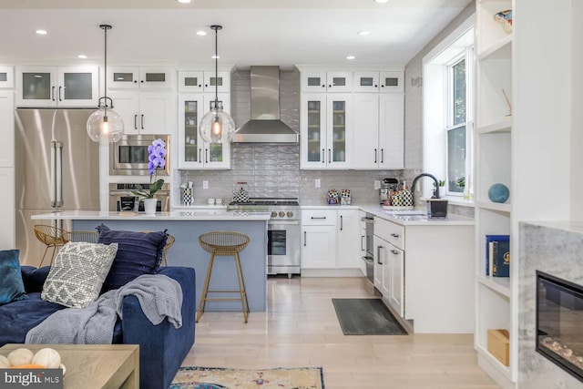 5116 Lawton Dr, Bethesda, MD 20816 - kitchen featuring wall chimney exhaust hood, high quality appliances, a sink, open floor plan, and a breakfast bar area