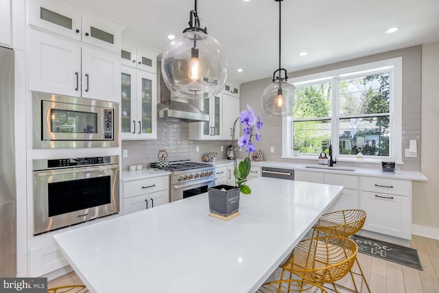 5116 Lawton Dr, Bethesda, MD 20816 - kitchen featuring stainless steel appliances, a sink, a breakfast bar area, decorative backsplash, and light wood-style flooring