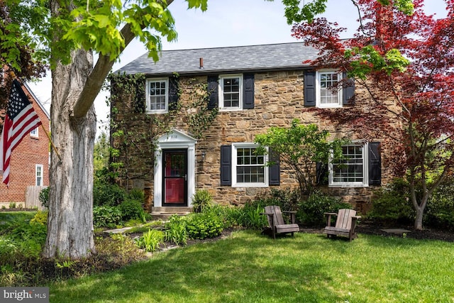 colonial inspired home with a front lawn and stone siding