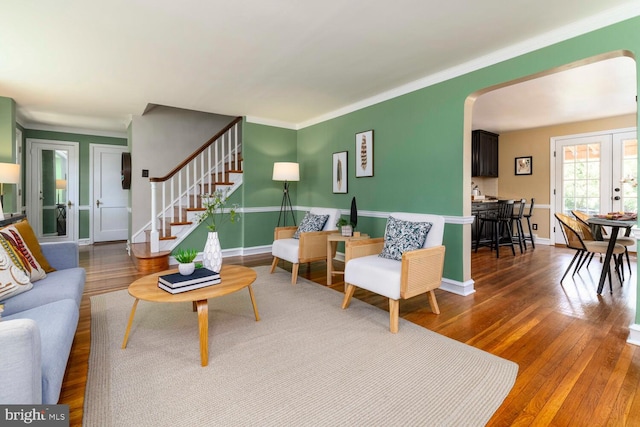 living room featuring french doors, arched walkways, baseboards, and wood finished floors