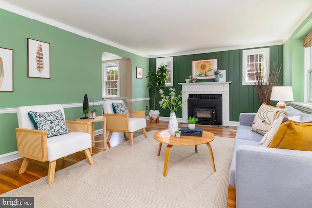 living room with arched walkways, ornamental molding, baseboards, and wood finished floors
