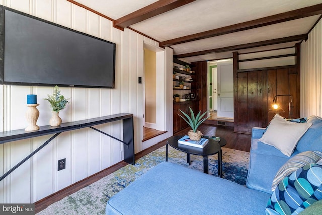 living area featuring beamed ceiling, wood finished floors, and visible vents