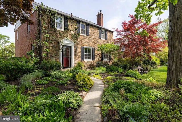 colonial home with a chimney and stone siding